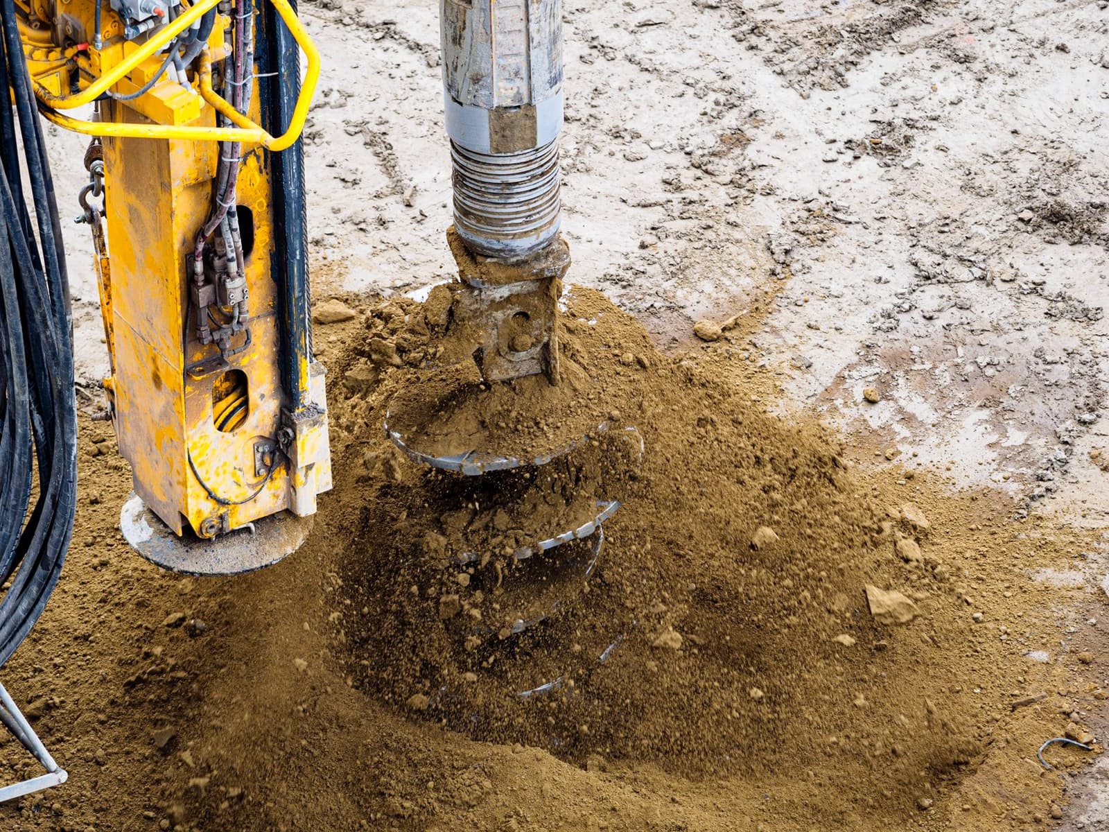 A drill auger boring into soil with cuttings piling up around it, under the headline Core or chips
