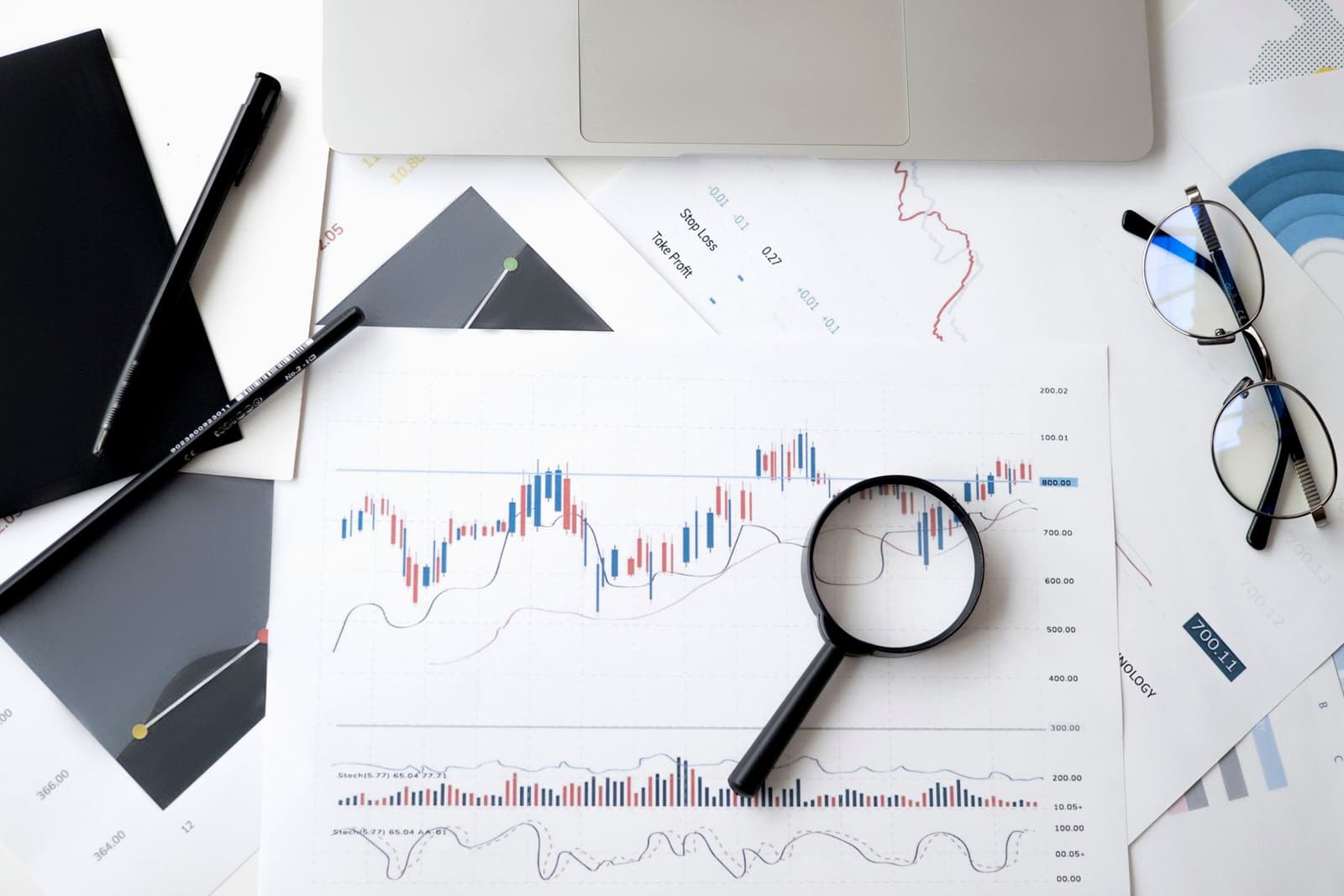 Printed price charts on a desk with a magnifying glass, pens and reading glasses, under the headline Market Cap vs EV