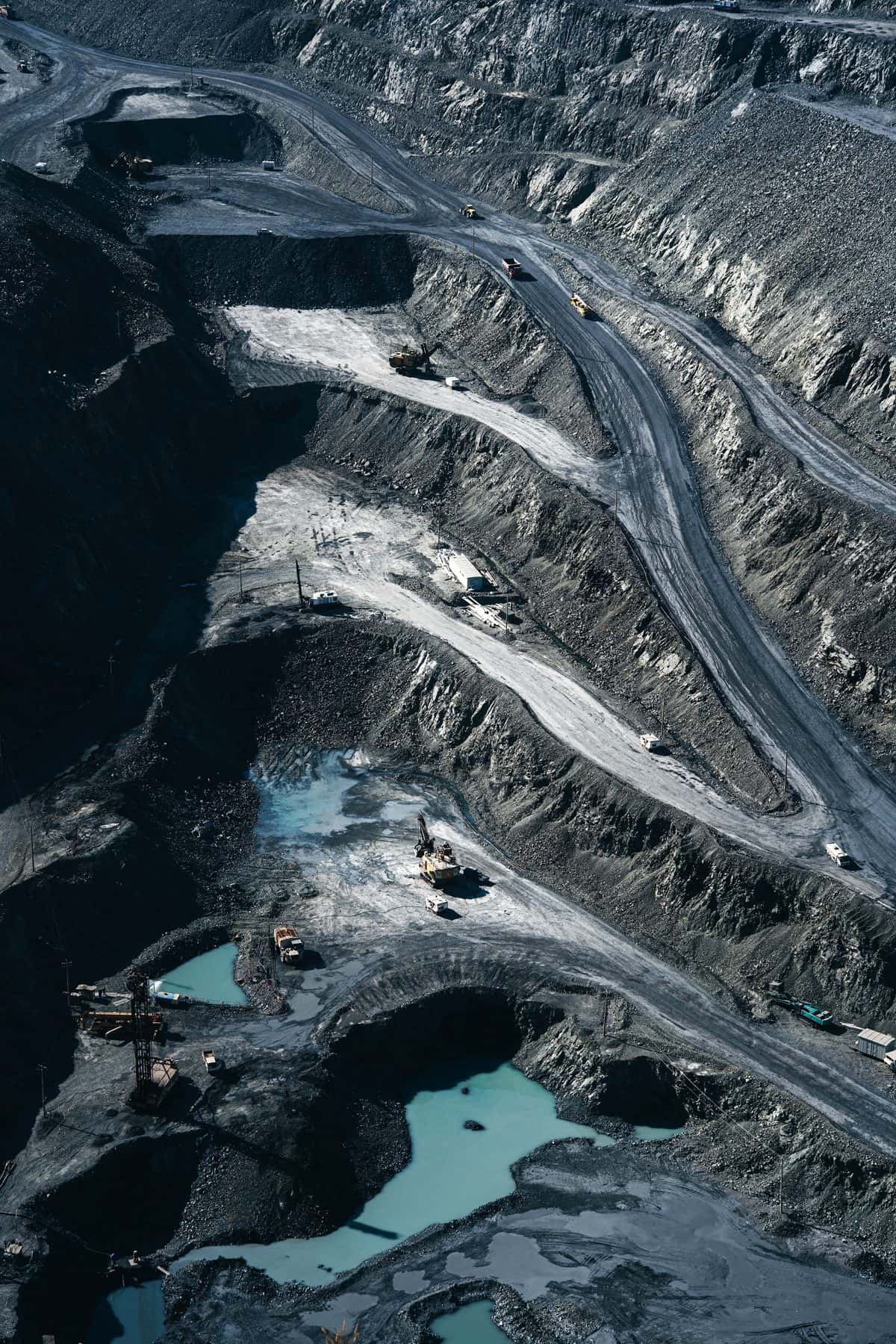 Aerial view of a terraced open-pit mine with haul roads, trucks and pools of blue water, under the headline The mine life cycle
