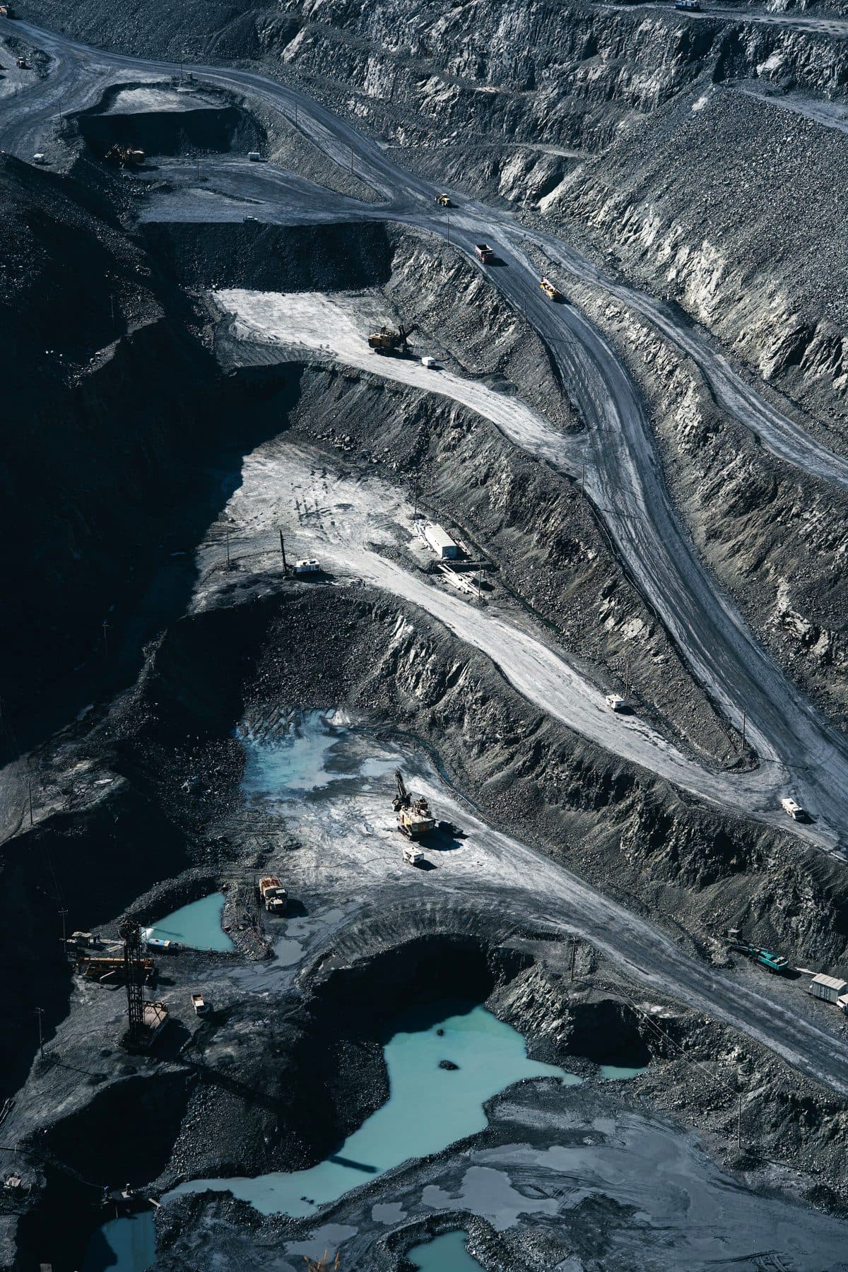 Aerial view of a terraced open-pit mine with haul roads, trucks and pools of blue water, under the headline The mine life cycle