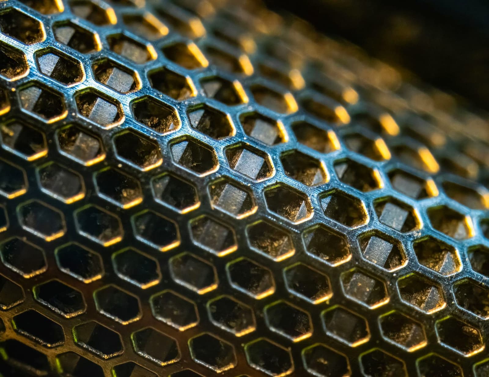 Close-up of a honeycomb metal mesh lit in gold and blue, under the headline Platinum Group Metals