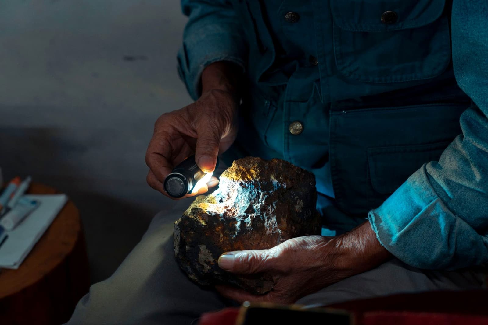 Hands examining a rock sample under a flashlight, under the headline Qualified person