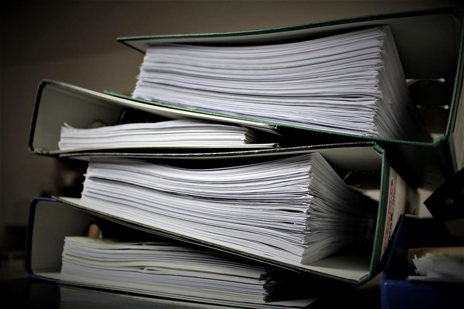 A stack of thick ring binders full of paper lying on top of each other, under the headline Consolidations
