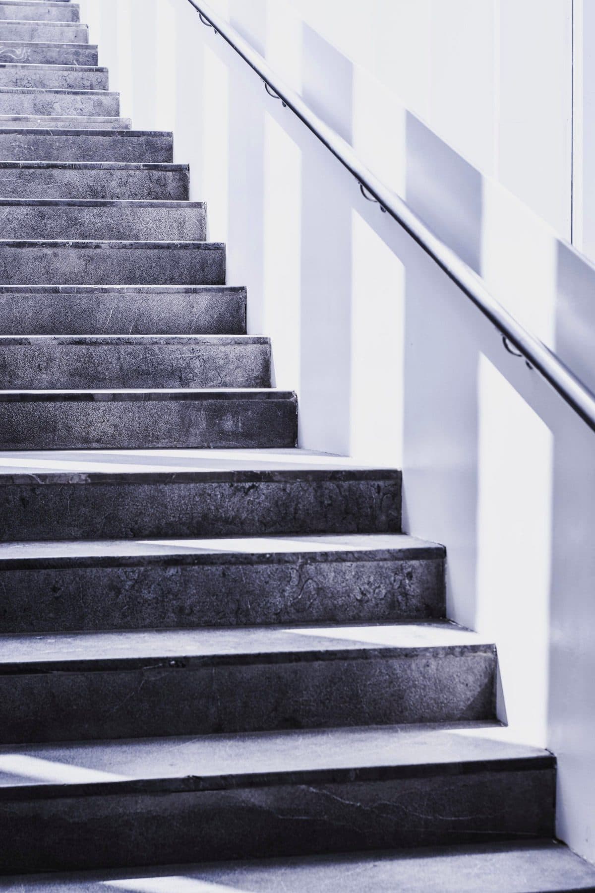 A flight of pale concrete stairs rising beside a handrail in black and white, under the headline TSXV tiers