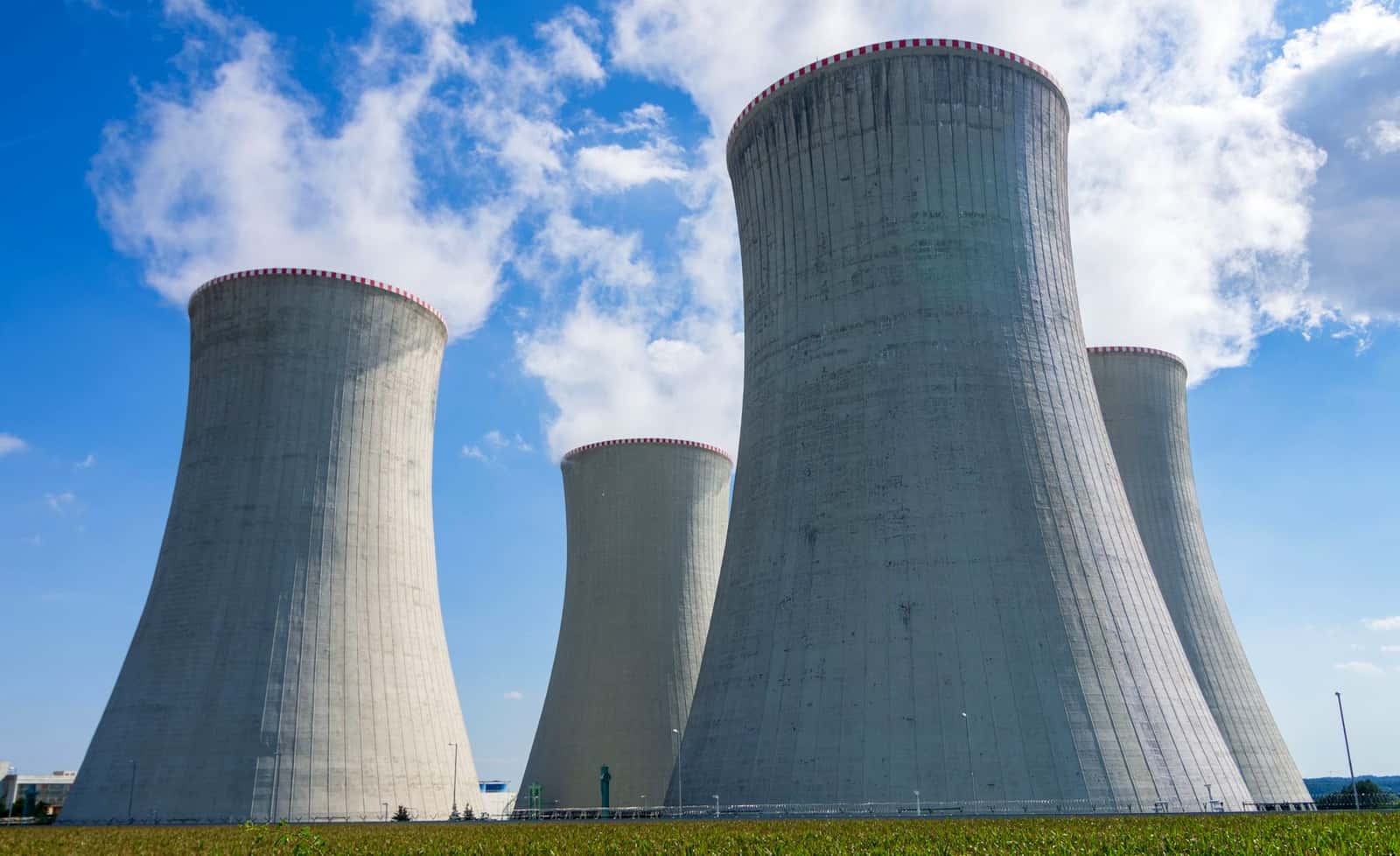 Concrete nuclear power plant cooling towers under a blue sky, under the headline Uranium