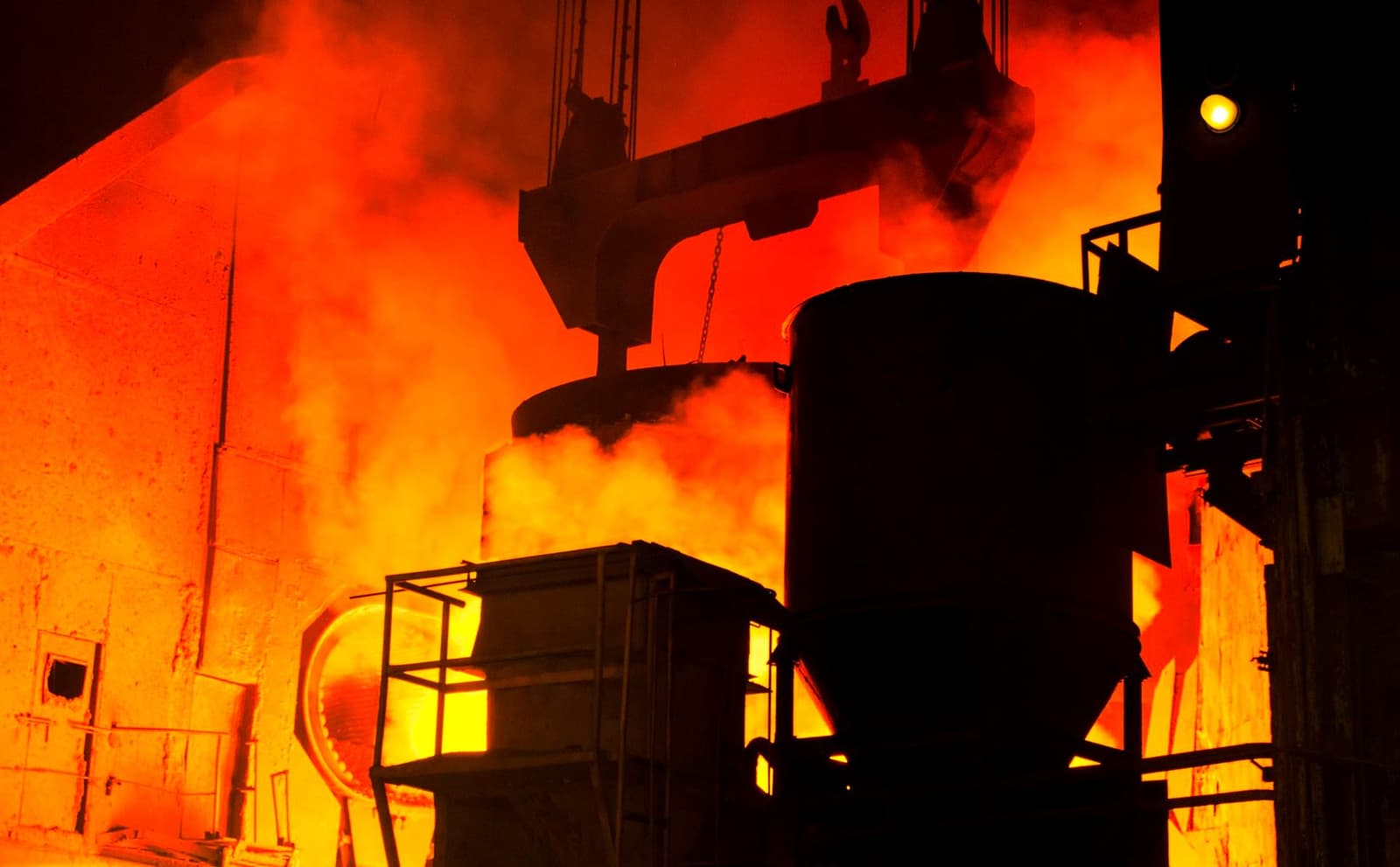 Molten metal pouring into a ladle inside a steel mill, lit orange by furnace heat, under the headline Vanadium